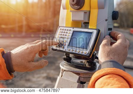 Site Engineer Operating His Instrument During Roadworks. Builder Using Total Positioning Station Tac