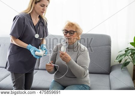 Elderly Woman Using Inhaler For Asthma And Respiratory Diseases At Home