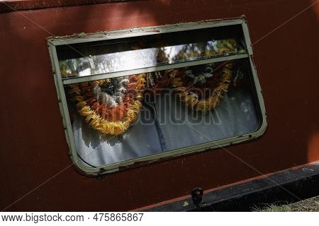 London - 05 21 2022: Window Of A Houseboat With Flower Garlands Moored On The Grand Union Canal
