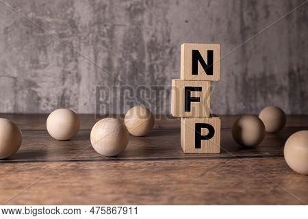 Text Nfp - Nonfarm Payrolls - On Wooden Blocks On The Background Of Financial Charts.