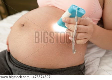 Pregnant Woman Feeling Happy At Home While Taking Care Of Her Child. The Young Expecting Mother Hold