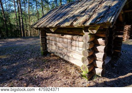 A Traditional Log Cabin Is Located In An Estonian Forest. Old Wooden Structure Small Hut In The Fore