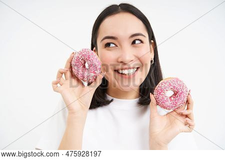 Close Up Portrait Of Cute Korean Woman, Smiling While Eating Pink Glazed Doughnuts, Likes Tasty Donn