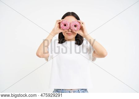 Cute Smiling Korean Woman, Looks Through Doughnut Holes, Eating Tasty Donnuts, Isolated Over White B