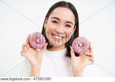 Close Up Portrait Of Cute Korean Woman, Smiling While Eating Pink Glazed Doughnuts, Likes Tasty Donn