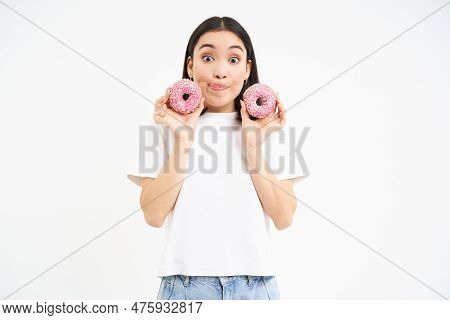 Cute Young Woman With Two Tasty Doughnuts, Tempted To Try Glazed Donnuts, White Background