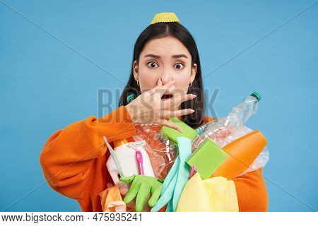 Portrait Of Woman Shuts Her Nose From Digust, Holding Stinky Garbage, Dirty Plastic Items And Empty 
