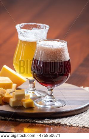 Glasses Of Belgian Yellow Blond And Dark Brown Beer Made In Abbey And Wooden Board With Variety Of B