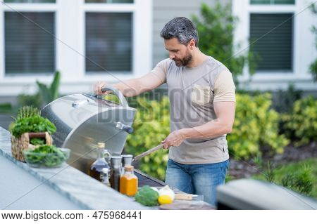 Hispanic Man Cooking On Barbecue In The Backyard. Chef Preparing Barbecue. Barbecue Chef Master. Han