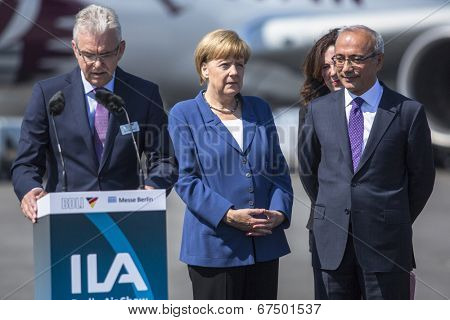 BERLIN, GERMANY - MAY 20, 2014: German Chancellor Angela Merkel (C) and Turkish Minister of transport Lutfi Elvan (R) open up the International aviation and space exhibition ILA.