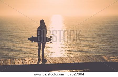 Beautiful and fashion young woman posing with a skateboard