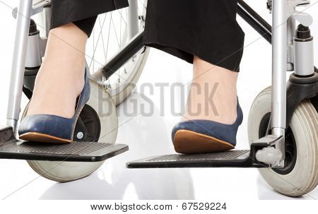 Close up on female's legs and shoues on wheelchair. Over white background.