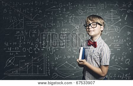 Genius boy in red glasses near blackboard with formulas