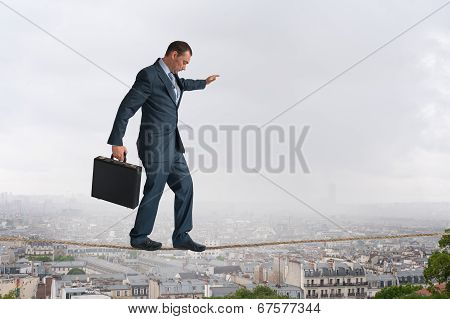 Businessman Walking Tightrope Above City