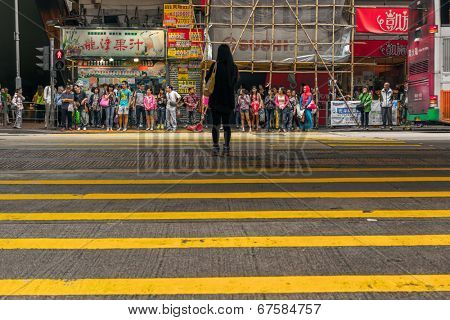 HONG KONG - MAY 11, 2014: Pedestrians wait to cross the street in the district of Mong Kok in Hong Kong. Mong Kok is one of the most crowded district in the world.