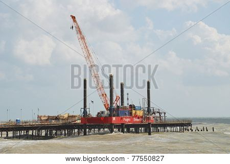 HASTINGS, ENGLAND - NOVEMBER 9, 2014: A 36mtr high crane mounted on a Fugro Seacore jackup barge takes part in the rebuilding of the Victorian pier. The pier was badly damaged by fire in October 2010.