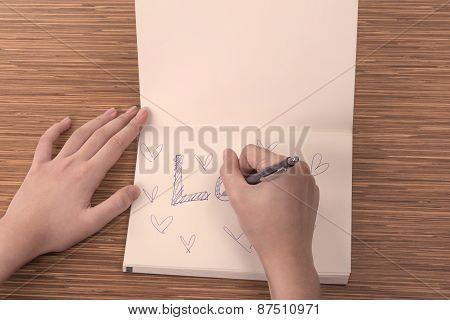Female Hand Writing In Notebook On Table