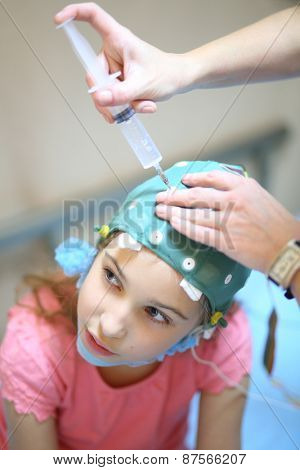 Medical worker will put electrode gel on the girls head for electroencephalography in hospital ward