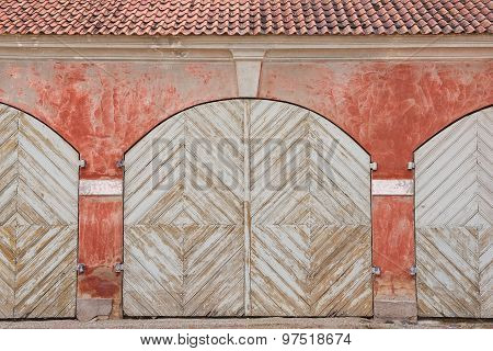 Weathered white painted wooden gates and the red wall of the stables next to Rundale, Latvia.