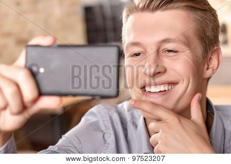 Smiling man doing selfie in cafe
