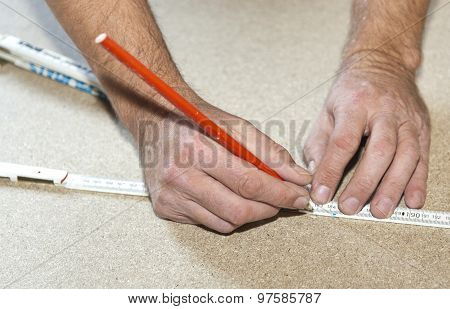 Man Uses A Yardstick To Mark The Chip Board
