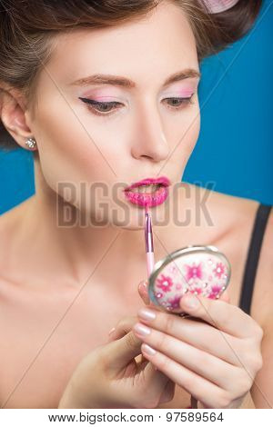 Sexy young pin-up girl doing make-up