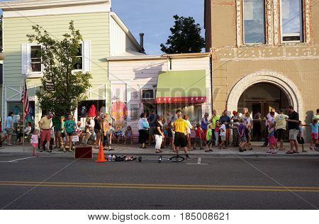 HARBOR SPRINGS, MICHIGAN / UNITED STATES - AUGUST 4, 2016: Crowds walk on the sidewalk and eat ice cream in front of Yummie's Ice Cream Store during the Street Musique event in downtown Harbor Springs.