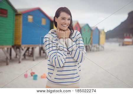 Smiling woman looking away while standing at beach