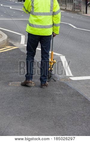 Surveyor using a survey or clickwheel to measure distance on a road