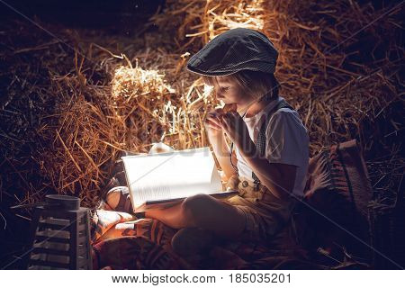 Sweet Child, Boy, Reading A Book On The Attic On A House, Sitting On A Hay Of Straw