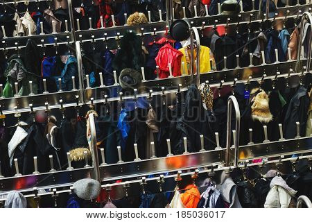 Variety of colored winter and autumn clothes on metal hangers in the wardrobe of a cinema, theater or exhibition. Top view of a large number of different clothes on hangers. Selective focus.