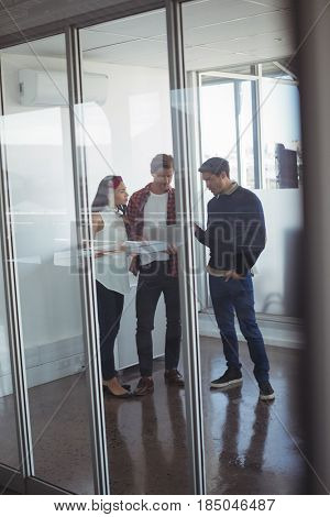 Full length of business colleagues seen through glass dicussing at office