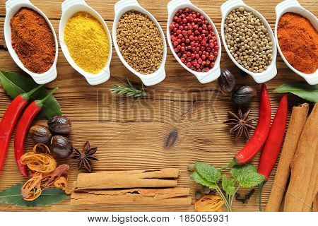 Spices in ceramic containers on wooden background. Food and cuisine ingradients.