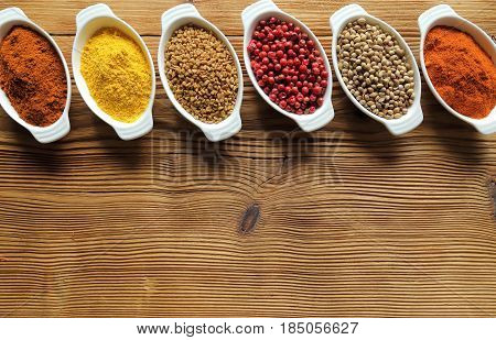 Spices in ceramic containers on wooden background. Food and cuisine ingradients.