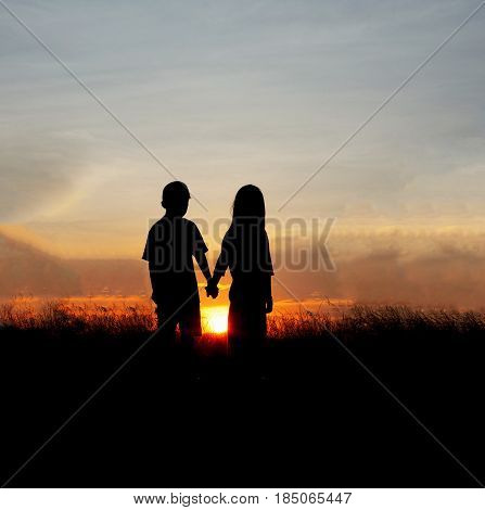 Silhouette  child of two on sunset mountain.