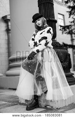 Woman in black and white clothes. Stylish retro urban girl trendy new age look. Accessories hat and Gloves. Fashion model posing in city stree. Photography portfolio.