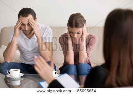 Depressed frustrated couple touching head, tired of constant arguing, emotional breakdown during therapy session, feels exhausted, desperate, unhappy, enervated. Love and marriage difficulties concept