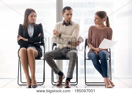 Male and female ambitious job seekers waiting for interview, looking at each other with hate and dislike, feeling jealous envious, rivalry and internal competition, get position and sidestep rivals