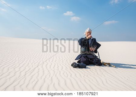 Man In Traditional Japanese Clothes, Concentratedly Dresses Helmet For Kendo