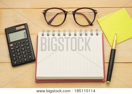 Top View. Empty Notebook, Calculator, Pust-it Note,glasses , And Ballpoint Pen All Of This Putting O