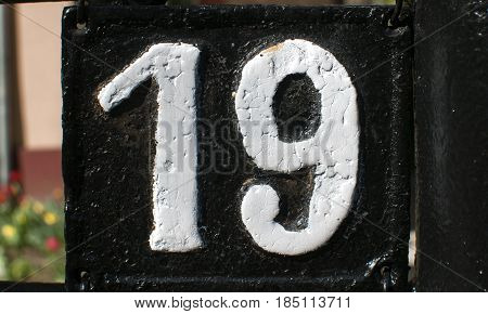 Old retro weathered cast iron plate with number 19 closeup