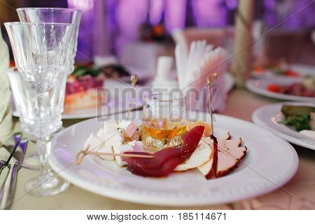 Delicious cheese plate, two kinds of cheese, Parmesan, blue, honey, carpaccio, walnut, french appetizer honey in the glass. Banquet serving at the festive table. selective focus.
