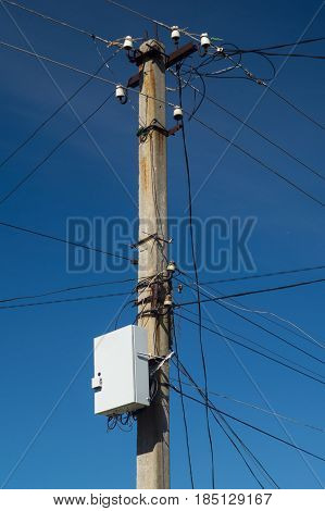 Electric pillar with wires and internet box on dark blue sky
