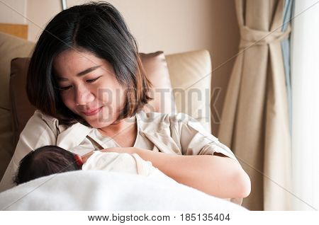 Mother breastfeeding her newborn baby beside window. Milk from mother's breast is a natural medicine to baby. Mother day bonding concept with newborn baby nursing.