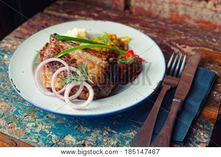 Grilled pork ribs with sauerkraut and mashed potatoes on old grunge peeled painted table, toned image