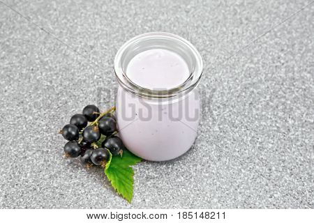 Milk cocktail with black currant in a glass jar with berries on the background of a granite table