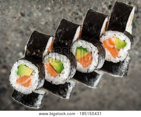 Sushi roll with salmon and avocado over cocnrete background