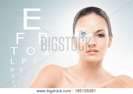 Beautiful woman with laser hologram and test vision table over cyan background.
