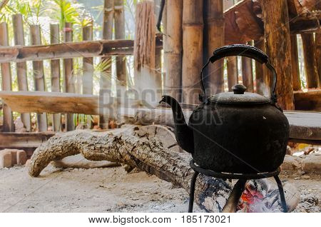 old vintage kettle with bunch of burning firewood to boil water in the old aluminum kettle with the scene of the shade of the housing of the hill tribes soft focus selective focus culture concept