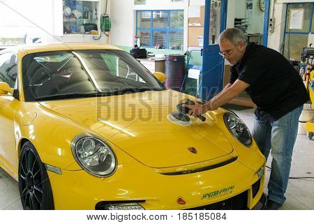 Mechanic Polishing Car In Auto Repair Shop.